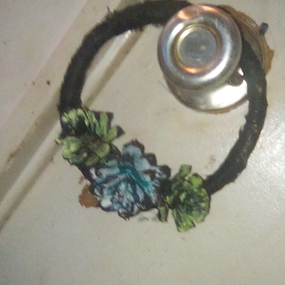 Small hand made wreath covered in black lace with three small "pinecone roses"